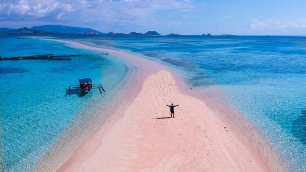 Visitor standing on the vibrant pink sandbar of Pink Beach during a Lombok snorkeling tour