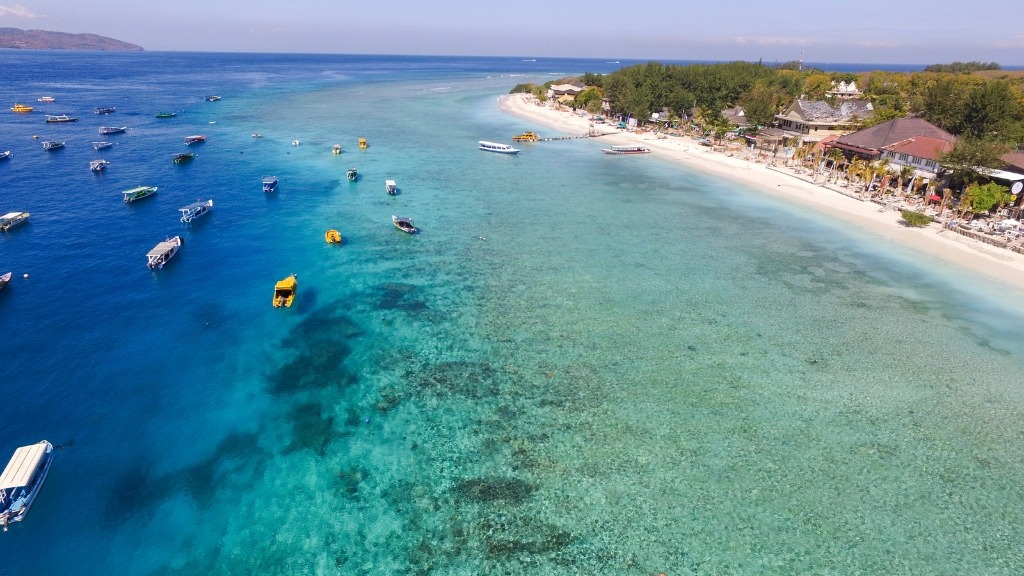 Snorkelers enjoying the clear, turquoise waters around a sandy Gili island in Lombok.