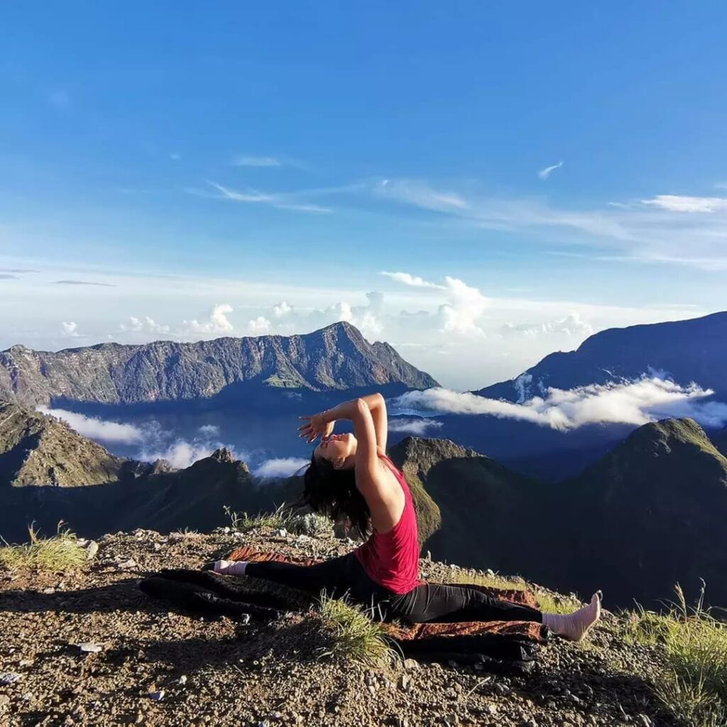 A woman practicing yoga on top of a mountain during a Lombok private tour.